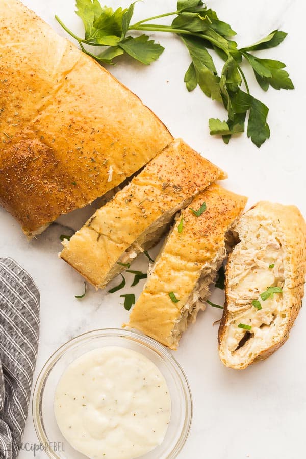 stromboli sliced overhead with alfredo sauce in a glass bowl on the side