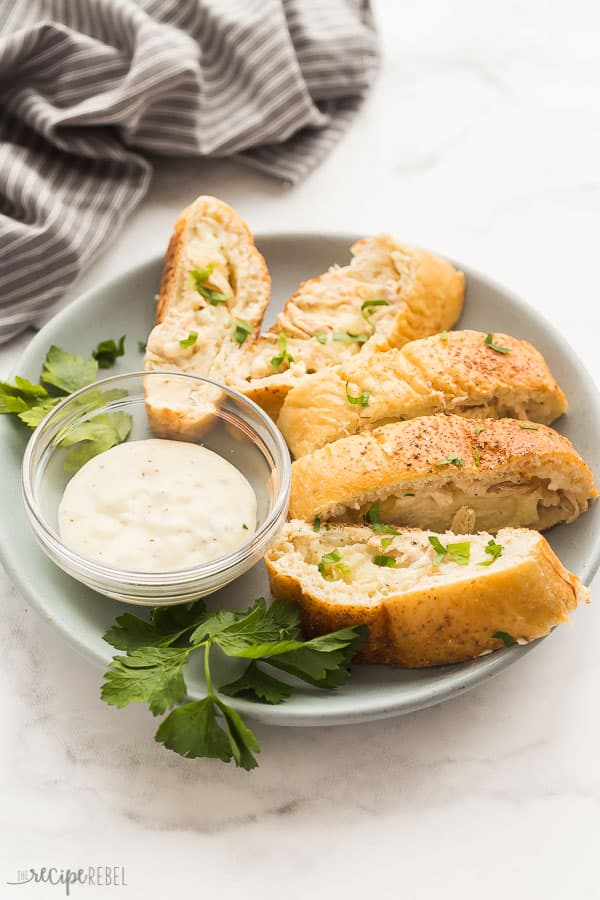 alfredo stromboli sliced on plate with alfredo sauce and fresh parsley