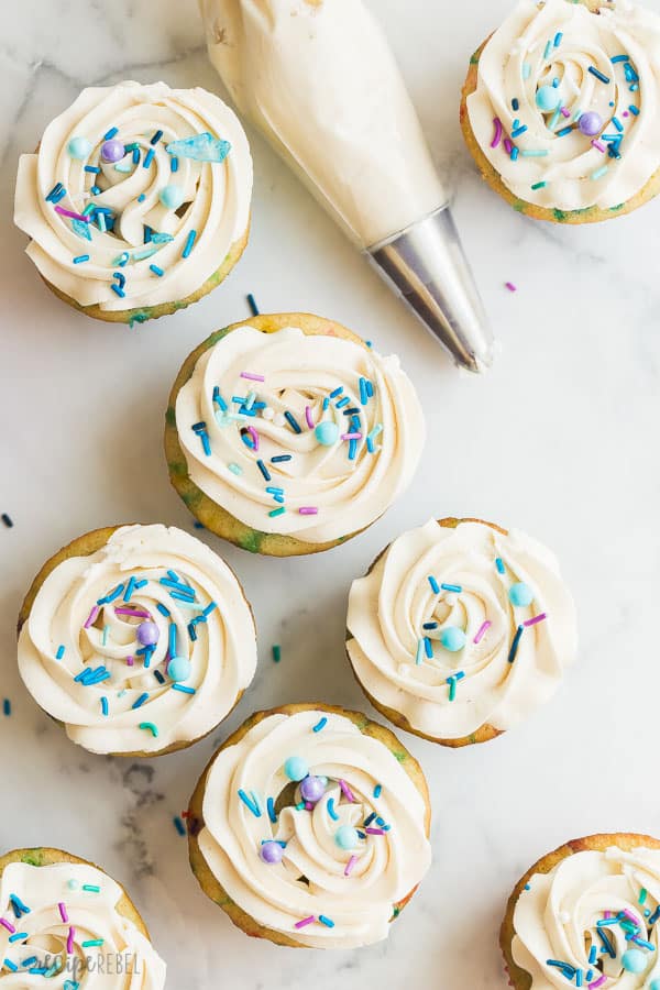 vanilla buttercream frosting on cupcakes with sprinkles overhead on white background