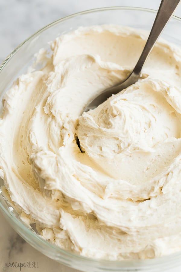 This easy Vanilla Buttercream Frosting is smooth and creamy and perfect on any cake or cupcake! #frosting #icing #dessert #recipes vanilla buttercream frosting in glass bowl with spoon stuck in