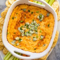 overhead image of buffalo chicken dip in white casserole dish with veggies around