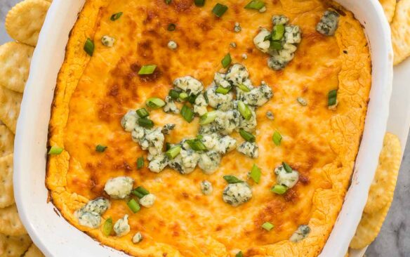 overhead image of buffalo chicken dip in white casserole dish with veggies around