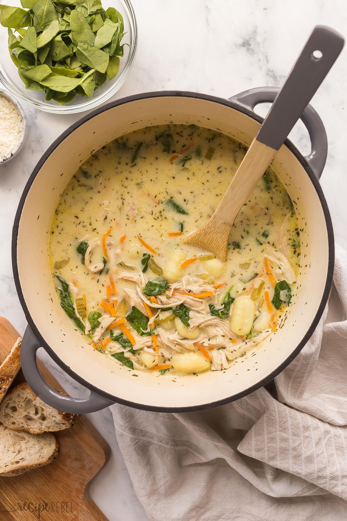 overhead image of pot of chicken gnocchi soup with wooden spoon