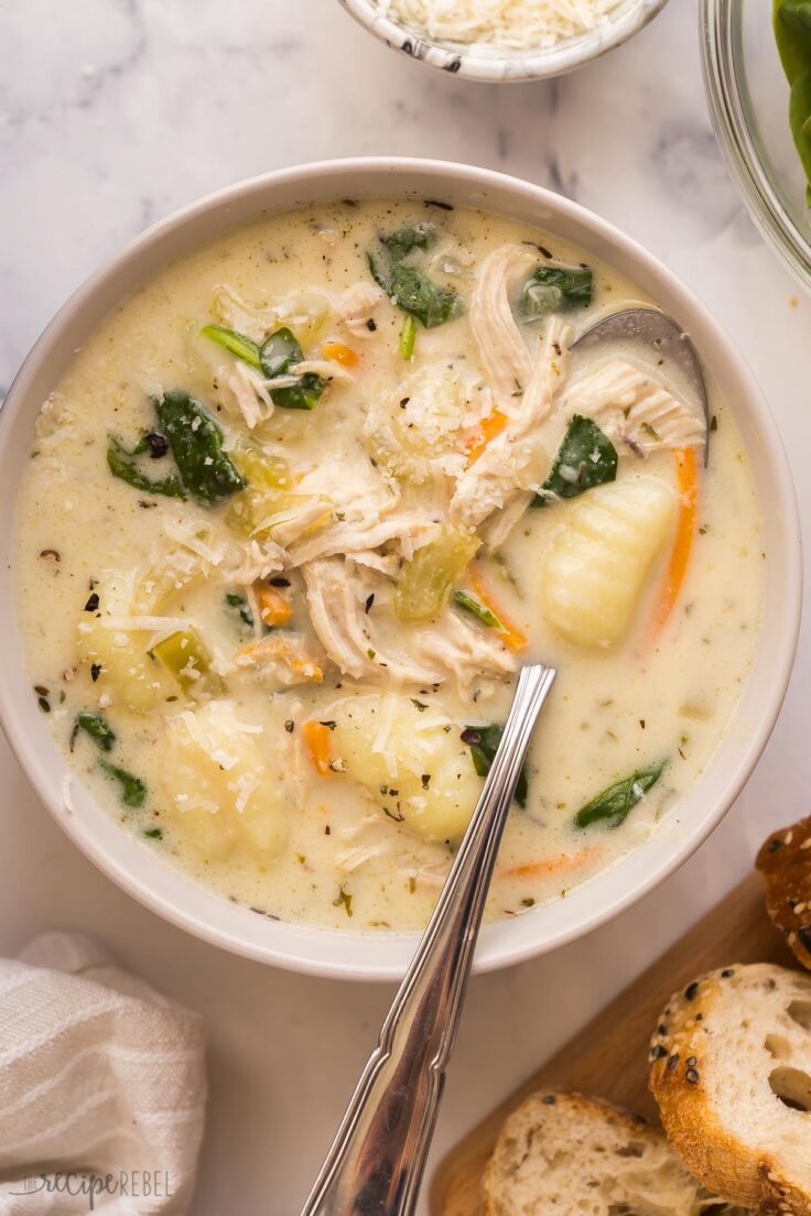 This Chicken Gnocchi Soup is better than Olive Garden! Loaded with tender chicken, chunks of vegetables, and spinach in a creamy, flavorful broth, it's made in 30 minutes! #soup #recipes #dinner | easy dinner ideas | easy recipes | chicken breast | chicken dinners | healthy soup overhead image of bowl of chicken gnocchi soup with spoon