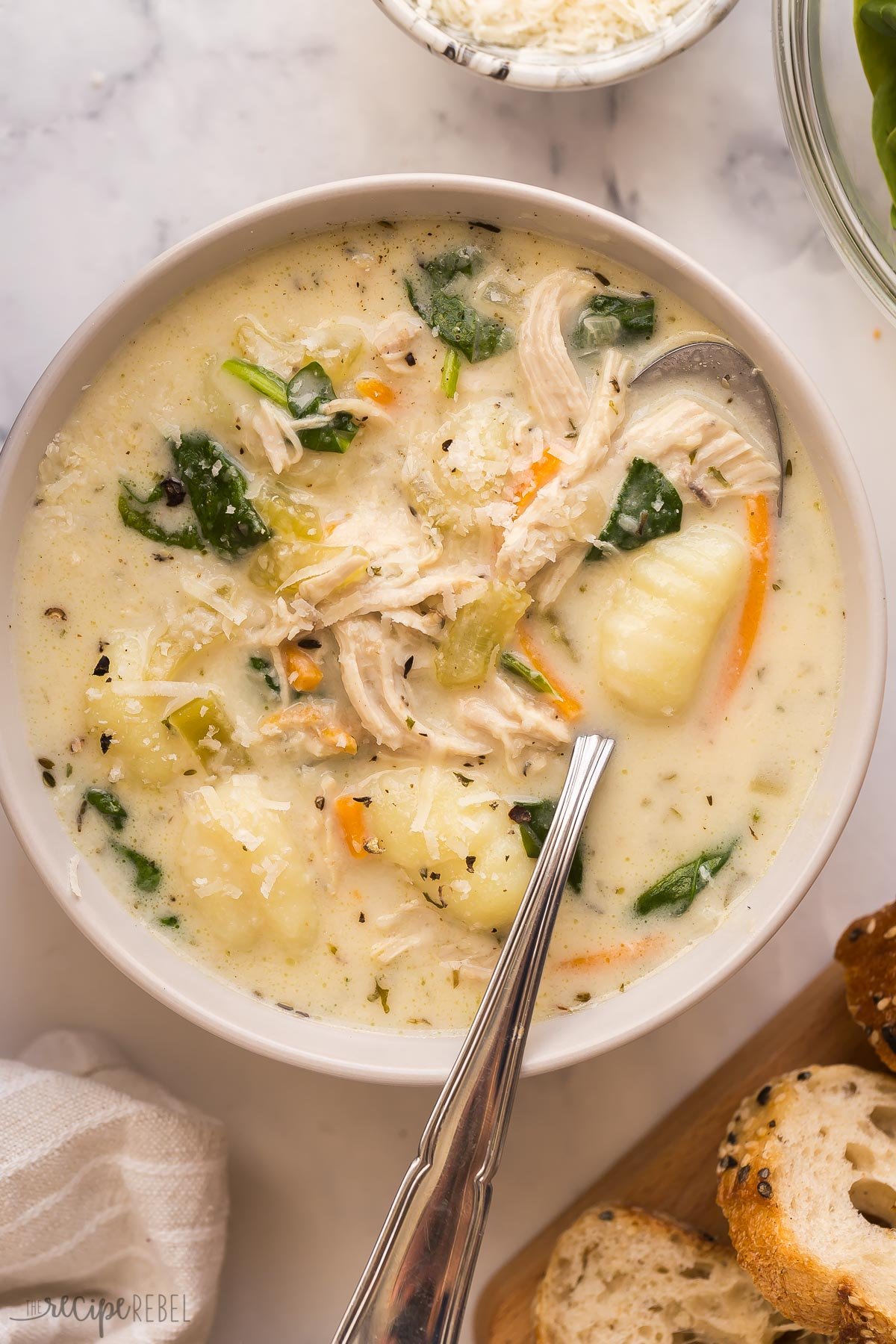This Chicken Gnocchi Soup is better than Olive Garden! Loaded with tender chicken, chunks of vegetables, and spinach in a creamy, flavorful broth, it's made in 30 minutes! #soup #recipes #dinner | easy dinner ideas | easy recipes | chicken breast | chicken dinners | healthy soup overhead image of bowl of chicken gnocchi soup with spoon