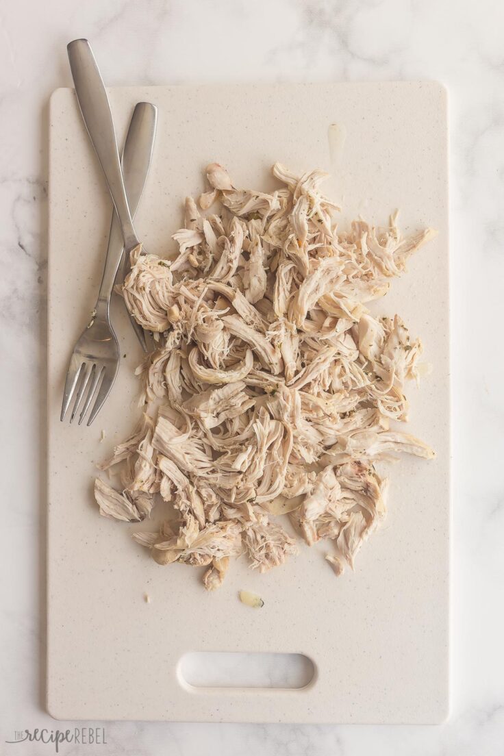 chicken breasts shredded on cutting board