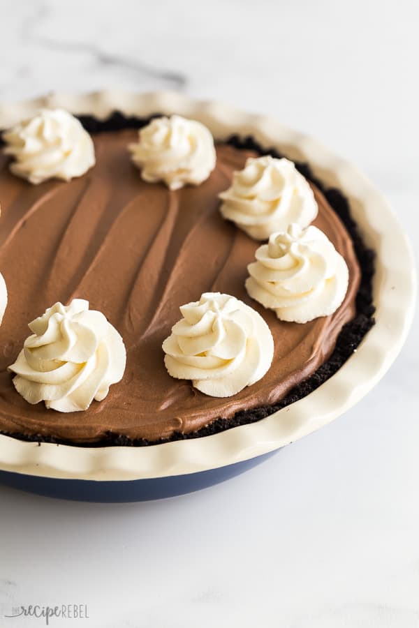 french silk pie whole in blue pie plate with whipped cream swirls
