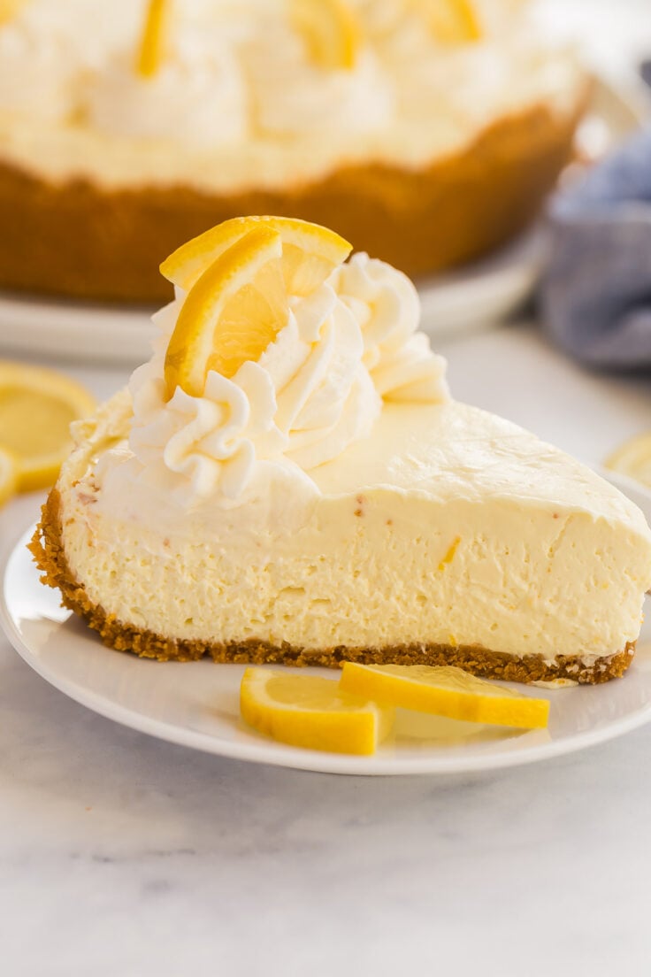 This No Bake Lemon Cheesecake is made with lemon juice and zest and no artificial flavors! It sets and slices perfectly and is even great frozen! #lemon #cheesecake #dessert | lemon recipes | no bake cheesecake | no bake desserts slice of no bake lemon cheesecake on white plate