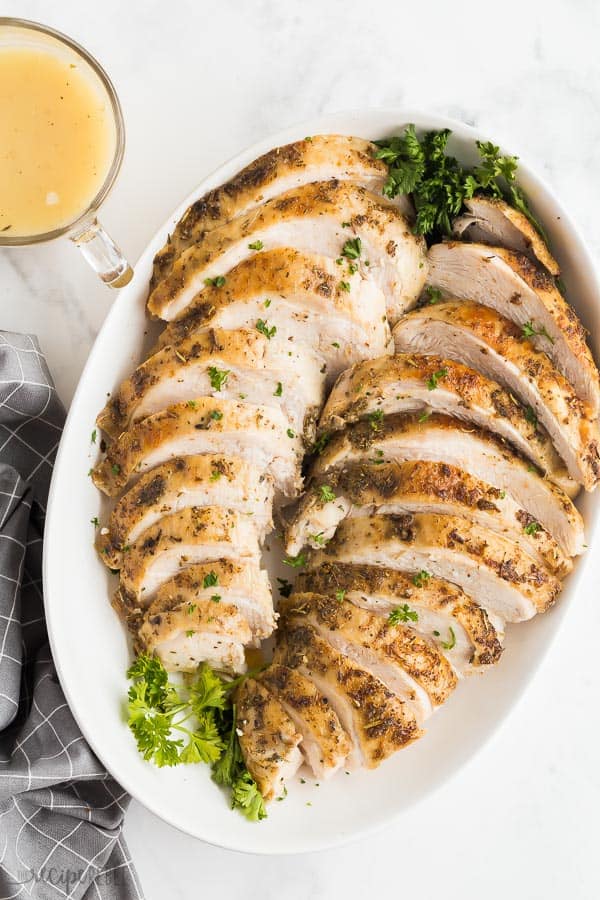 sous vide turkey breast overhead on white serving platter with fresh parsley
