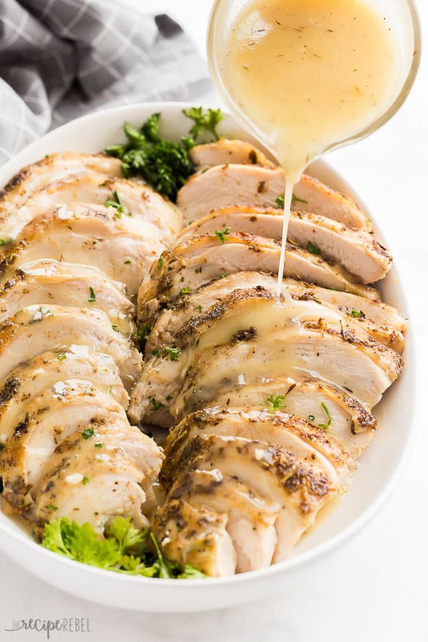 sous vide turkey with gravy in white serving plate with parsley on white background