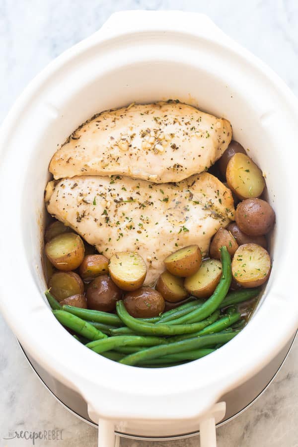 This Slow Cooker Garlic Butter Chicken and Potatoes is an easy hands-off meal with just 5 minutes prep time! Juicy chicken breasts and tender potatoes in a garlic butter sauce. With step by step recipe video down below! #crockpot #slowcooker #chickenbreast #dinner #recipes crockpot chicken breast and potatoes with green beans in white slow cooker