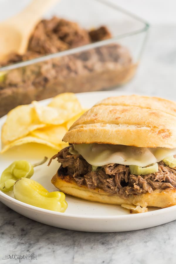 crockpot italian beef sandwich on ciabatta bun with cheese and chips on the side