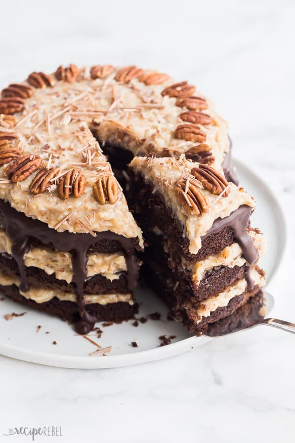 german chocolate cake on white plate on white background with one slice being pulled out