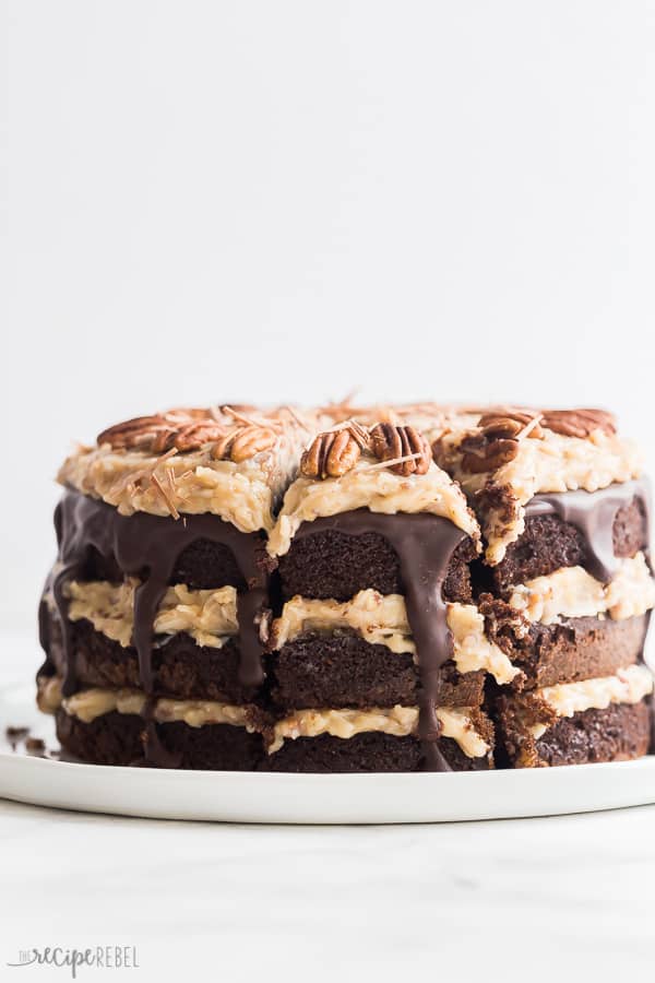 german chocolate cake whole with one slice cut on white plate