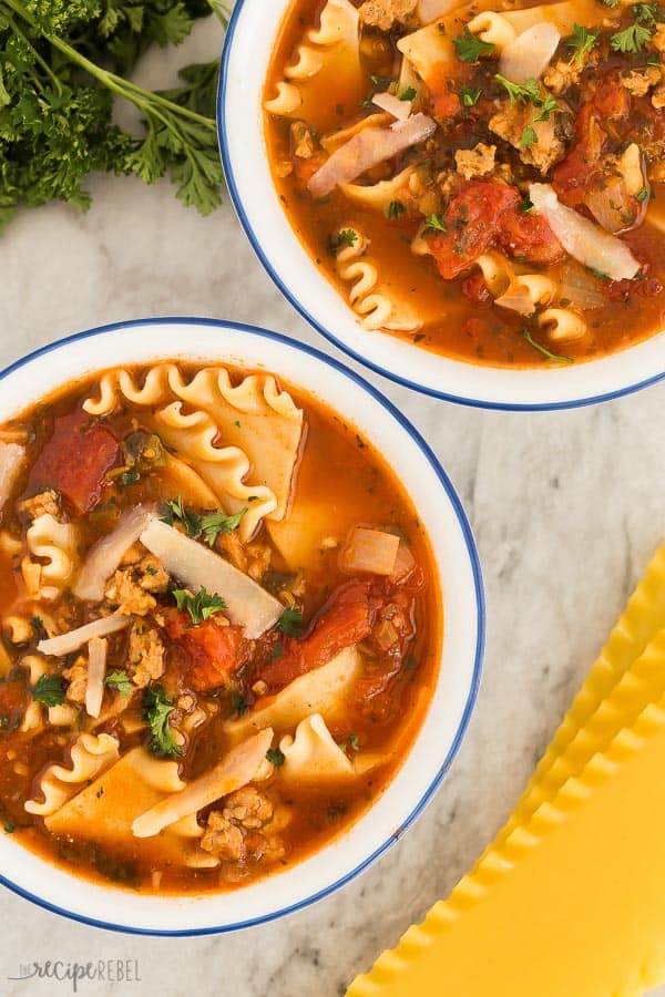 lasagna soup overhead in two white bowls with blue rims and uncooked lasagna noodles