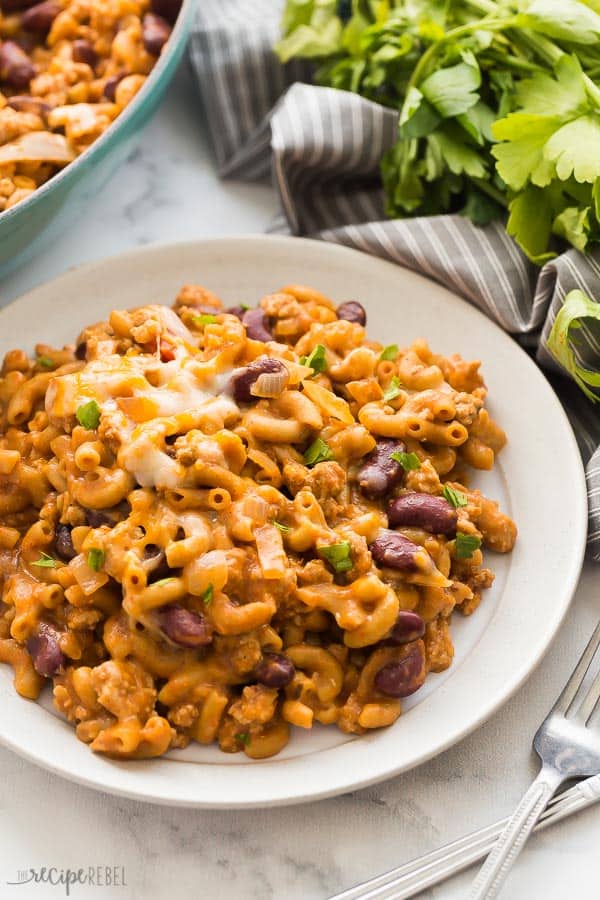 turkey chili mac and cheese on white plate with grey towel and parsley in the background