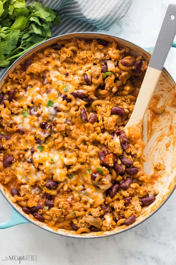 This Turkey Chili Mac and Cheese is a hearty, healthy one pot pasta that comes together in 30 minutes or less! With step by step recipe video. #dinner #recipes #turkey #pasta #macaroni turkey chili mac and cheese overhead in pan with blue handles on marble