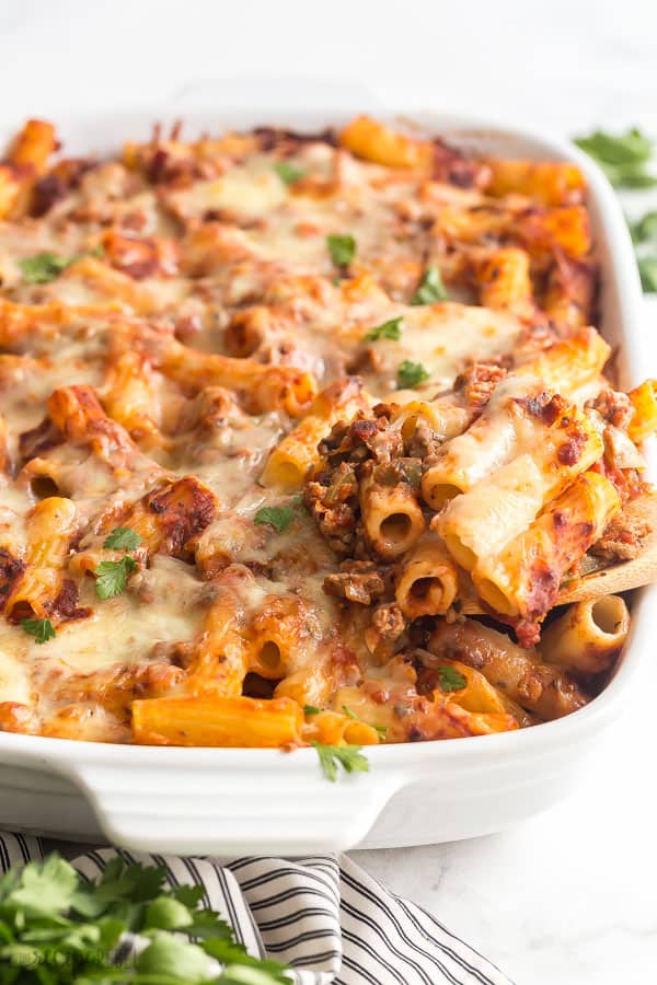 baked ziti scooped out of white casserole dish up close