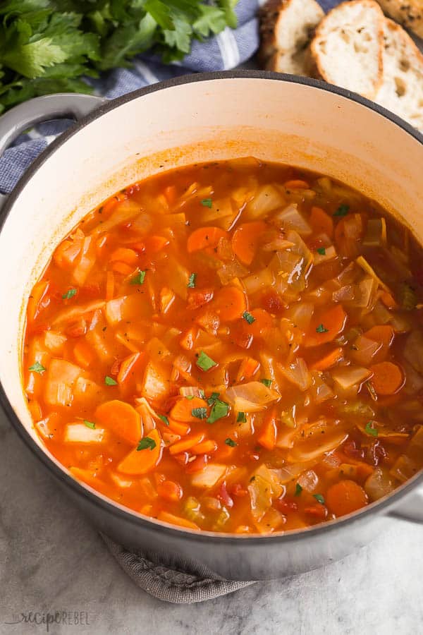 cabbage soup in grey dutch oven with bread in the background