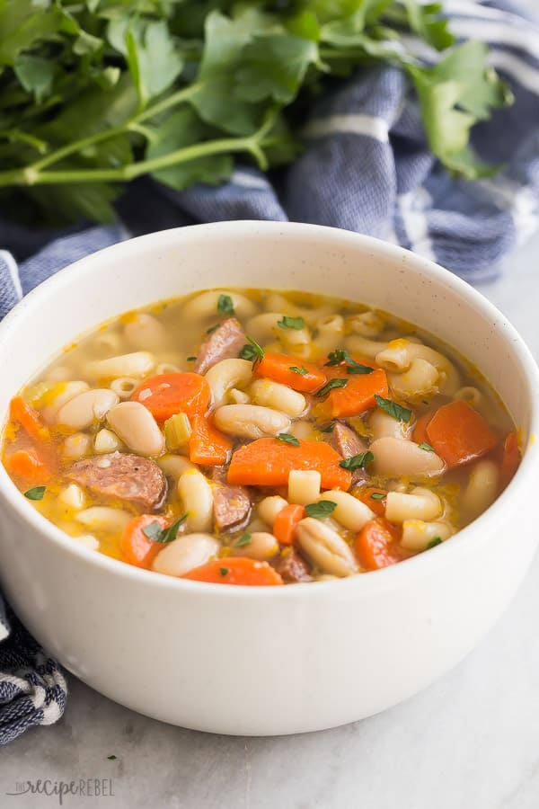 This Smoked Sausage Minestrone Soup is made with SIX ingredients and loaded with flavor! Pasta, beans, veggies and sausage makes it a hearty and comforting meal. #soup #healthy #dinner #recipes smoked sausage minestrone in a bowl with blue towel and parsley in the background