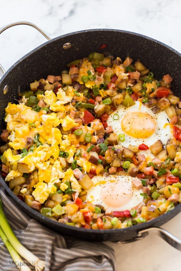 breakfast skillet potatoes and eggs with vegetables in large black pan