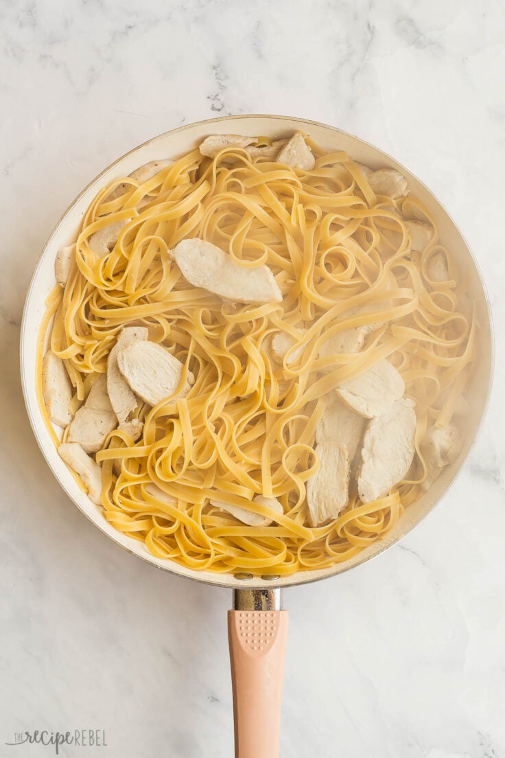 cooked fettuccini noodles with chicken in white skillet before adding cream