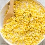 square image of creamed corn in white skillet.