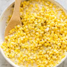 square image of creamed corn in white skillet.