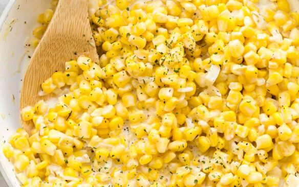 square image of creamed corn in white skillet.