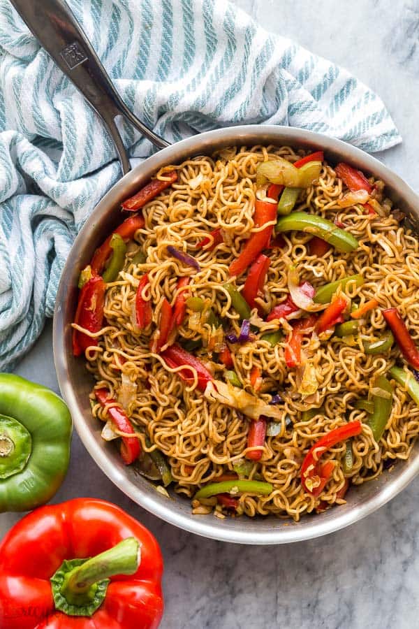 veggie lo mein in pan with blue towel and peppers in background