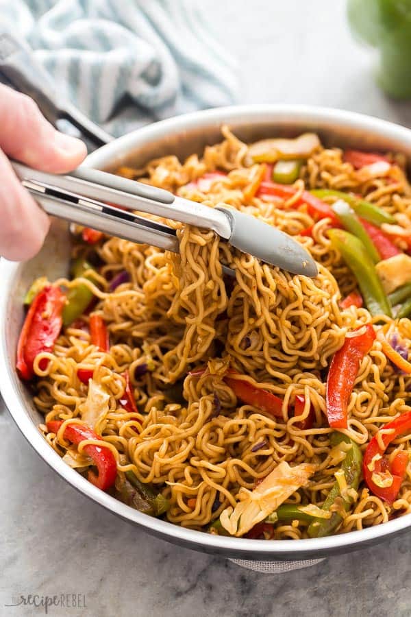 vegetable lo mein being scooped with grey tongs