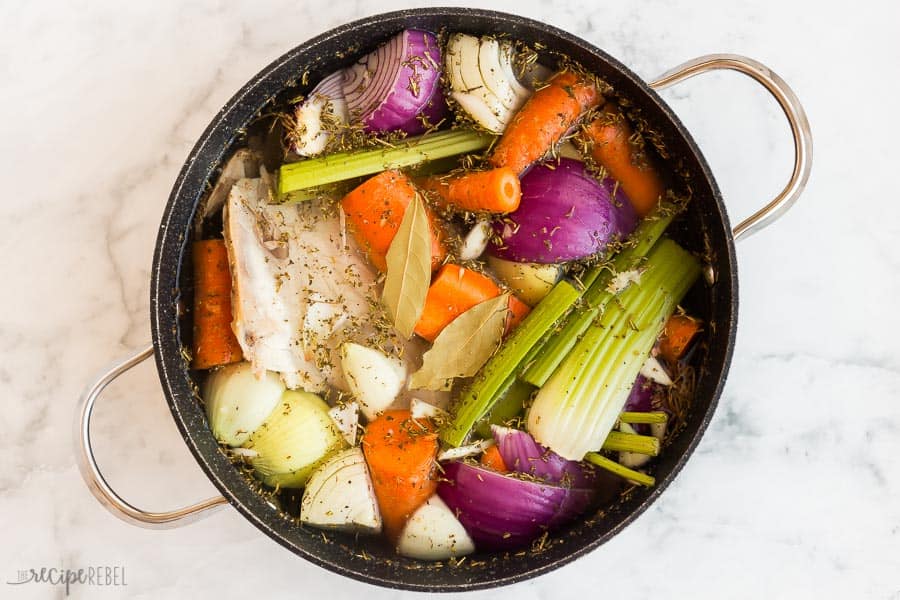 turkey stock with vegetables in black pot overhead on marble