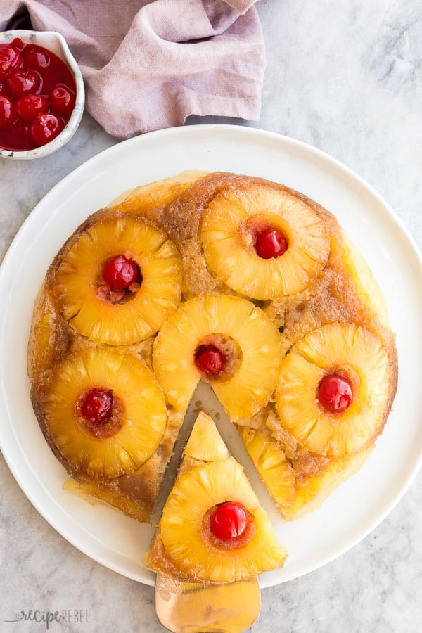 pineapple upside down cake overhead on white plate with slice being pulled out