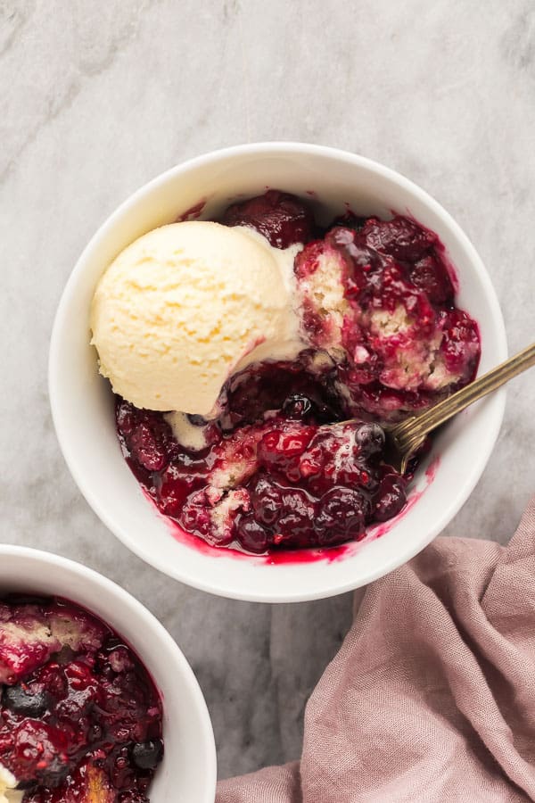 slow cooker berry cobbler with ice cream up close overhead with pink towel