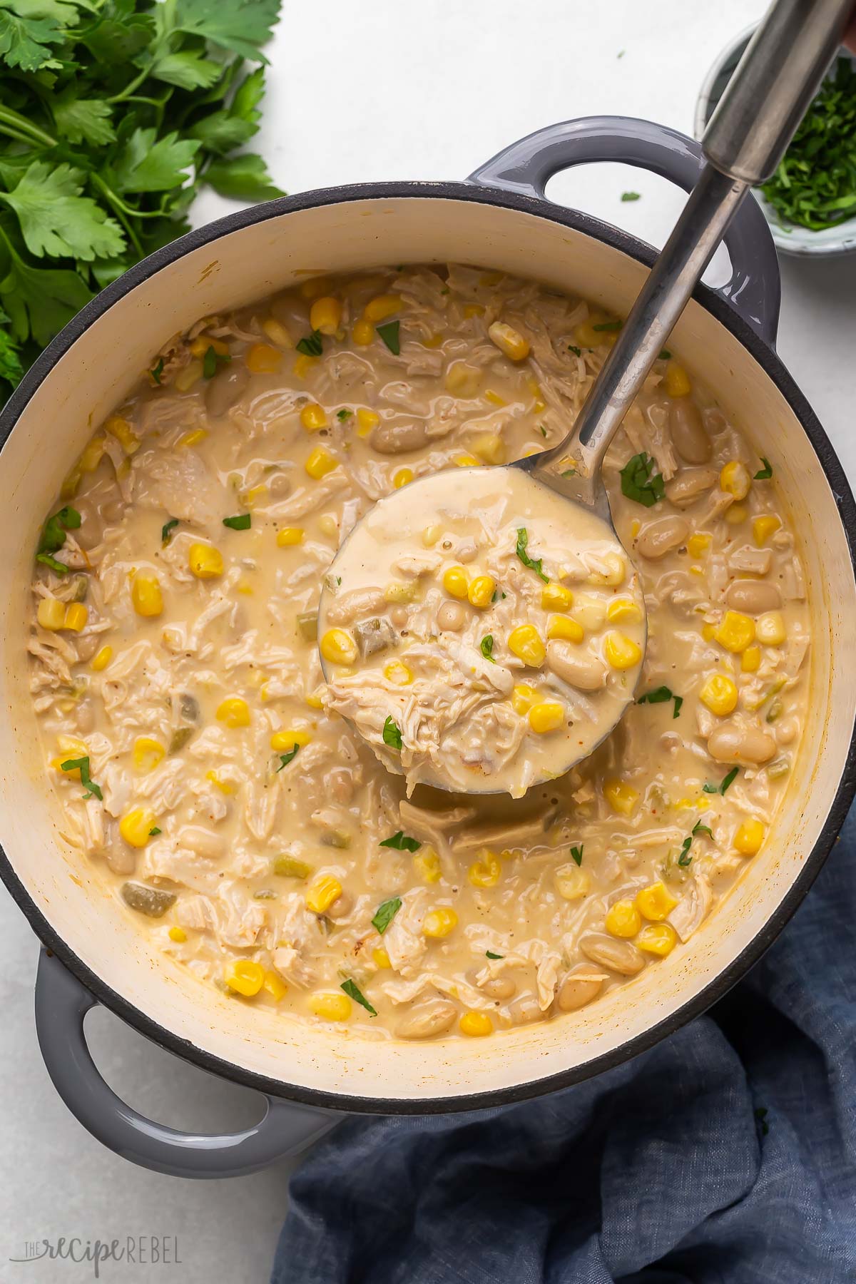 overhead image of white chicken chili with metal ladle scooping.