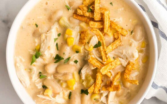 overhead image of bowl of white chicken chili with tortilla strips