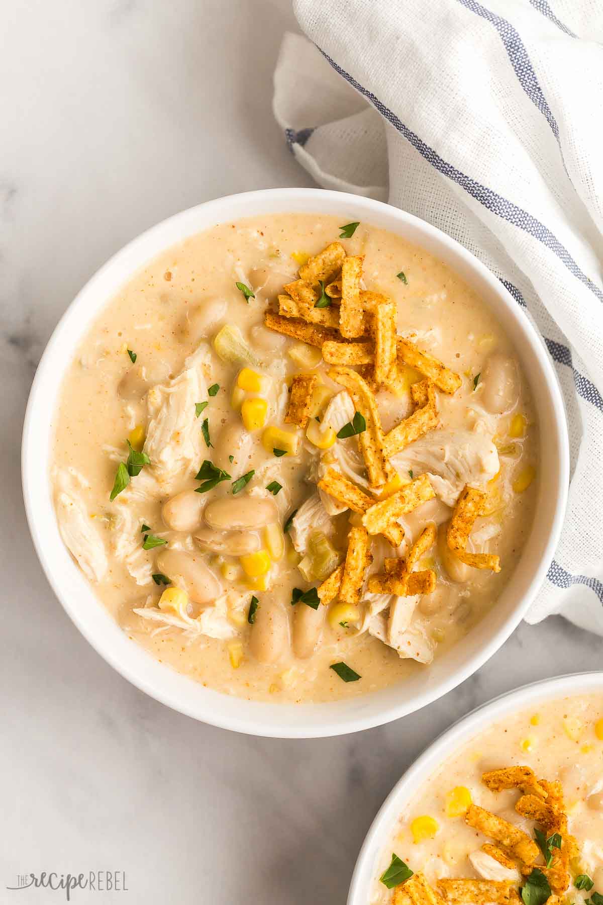 This White Chicken Chili is ultra thick and creamy, with shredded chicken, white beans and corn and just the right amount of spice! Make ahead and freezer friendly, perfect for pantry cooking. #chili #chicken #chickenbreast #dinner overhead image of bowl of white chicken chili with tortilla strips
