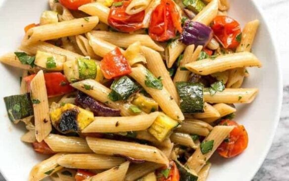 Grilled vegetable pasta salad on a white plate.