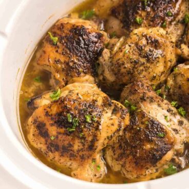 close up image of bone in chicken thighs in crockpot.