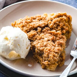 A slice of rhubarb crisp pie and a scoop of ice cream on a plate.