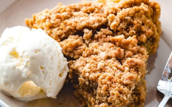 A slice of rhubarb crisp pie and a scoop of ice cream on a plate.