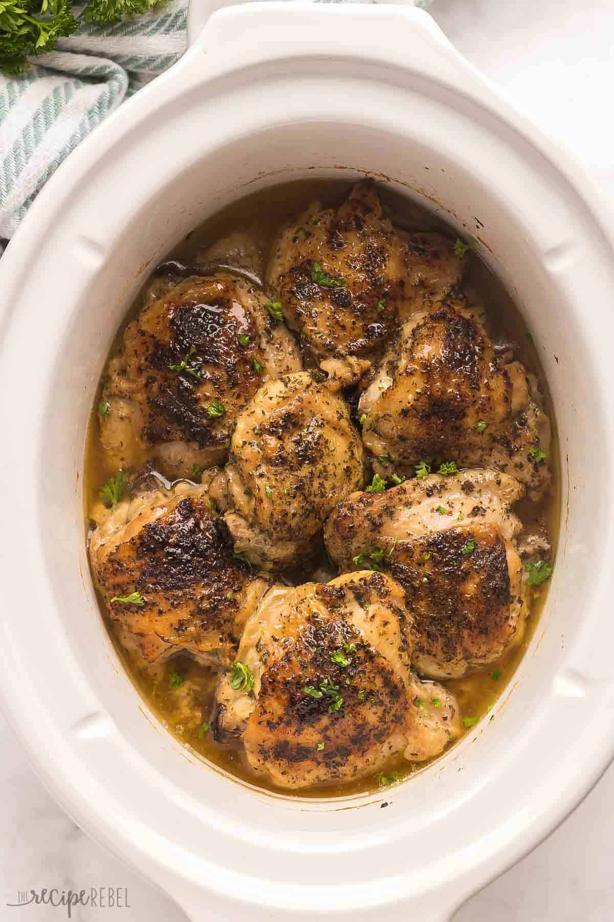 overhead image of bone in chicken thighs in white slow cooker.