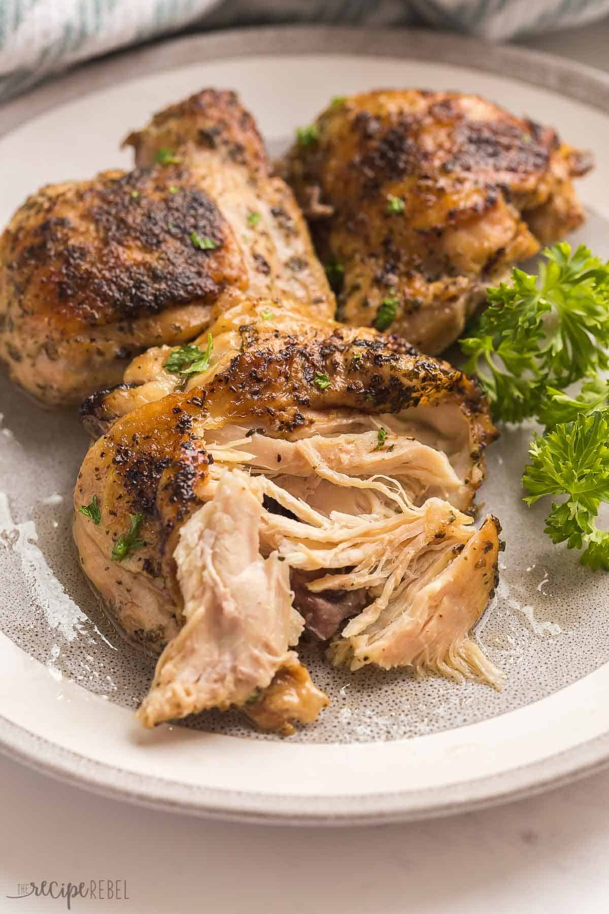 crockpot chicken thighs on grey plate pulled apart with fork.