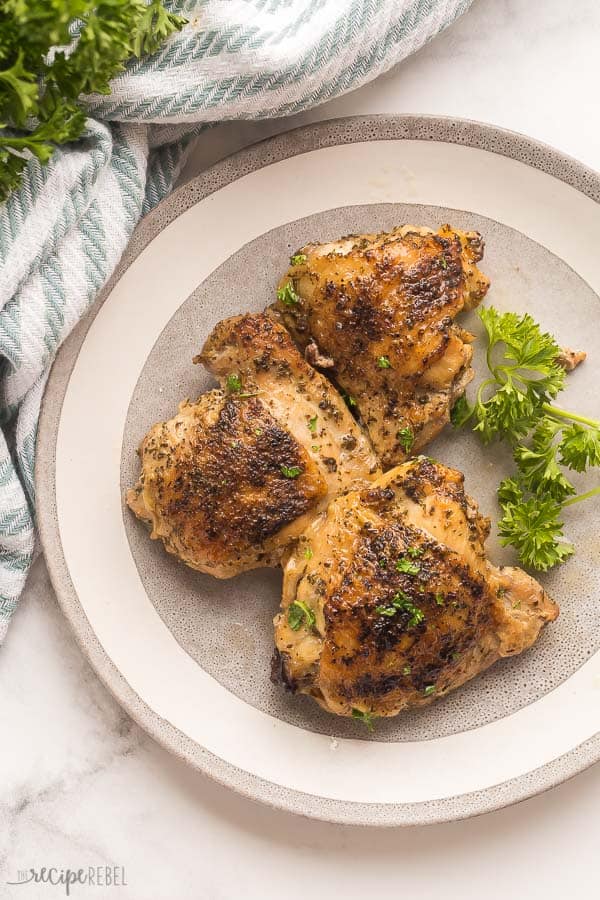 crockpot chicken thighs with skin on a grey plate overhead