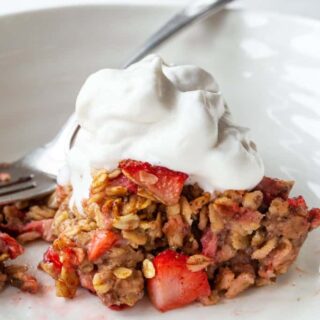 A serving of strawberry rhubarb oatmeal on a plate topped with whipped cream.