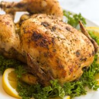 crockpot whole chicken broiled on white plate with lemon and parsley