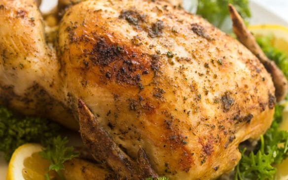 crockpot whole chicken broiled on white plate with lemon and parsley