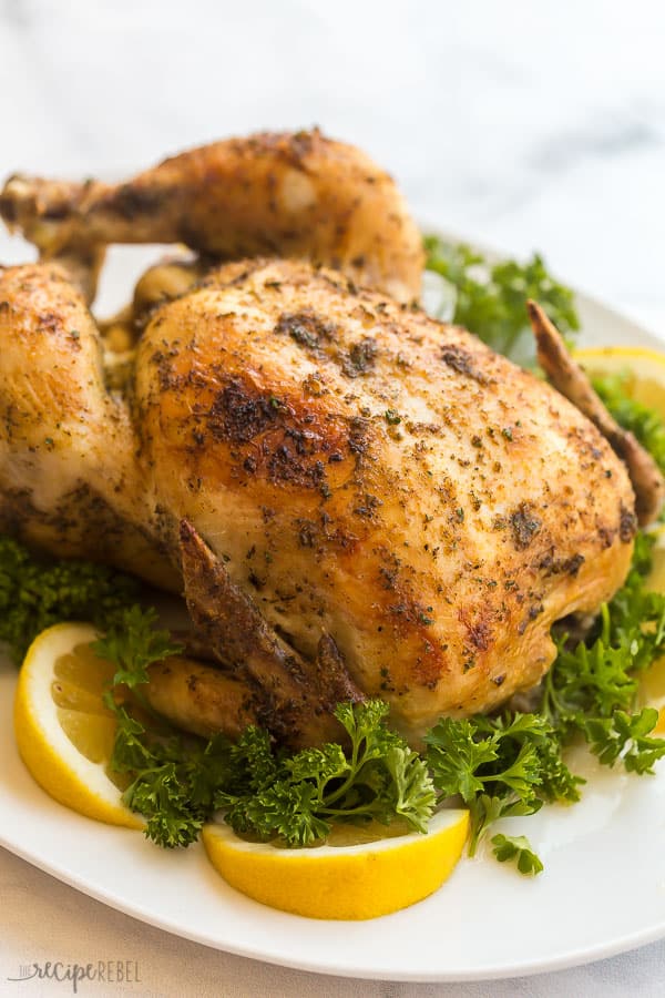 crockpot whole chicken broiled on white plate with lemon and parsley