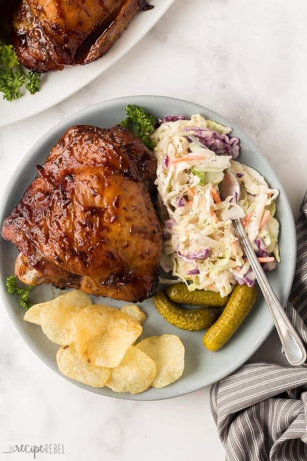 grilled turkey thighs on blue plate with coleslaw pickles and chips
