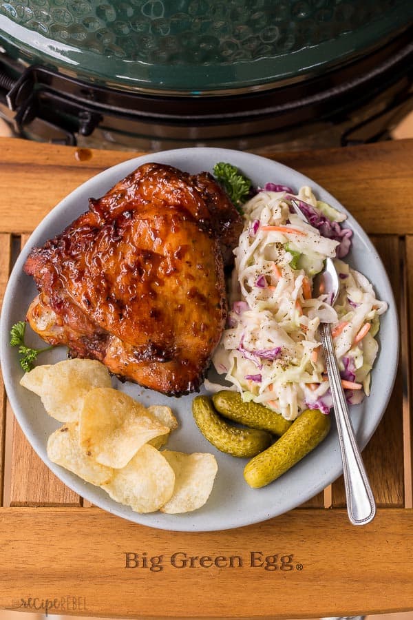 grilled turkey thighs on plate with coleslaw chips and pickles on big green egg